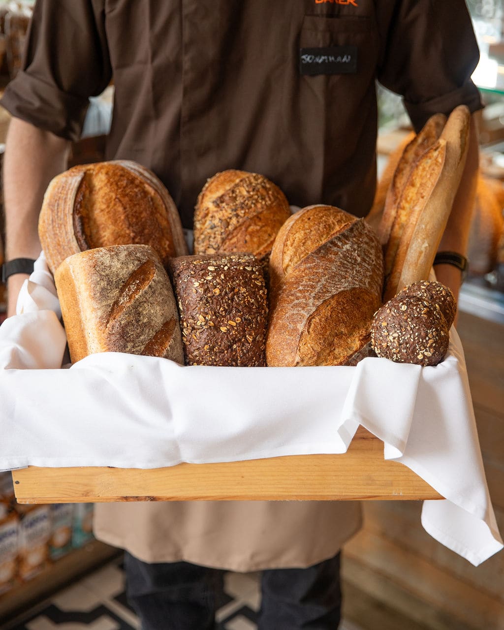 A team member holding a basket of fresh loaves